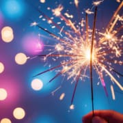 Person holding sparkler during fireworks on the fourth of july